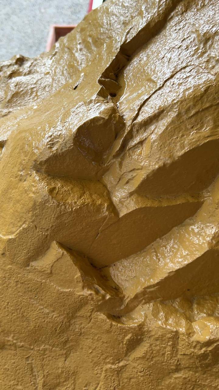 Vue rapprochée de la surface dorée de la Pierre de la Divinité Dragon, luisante d'eau